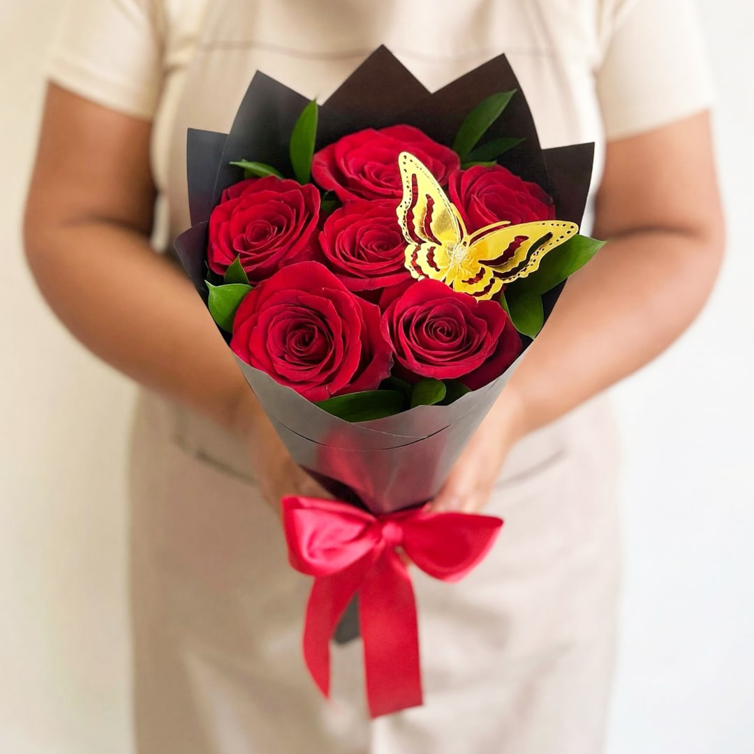Bouquet of red roses wrapped in black paper with a red ribbon and butterfly decoration