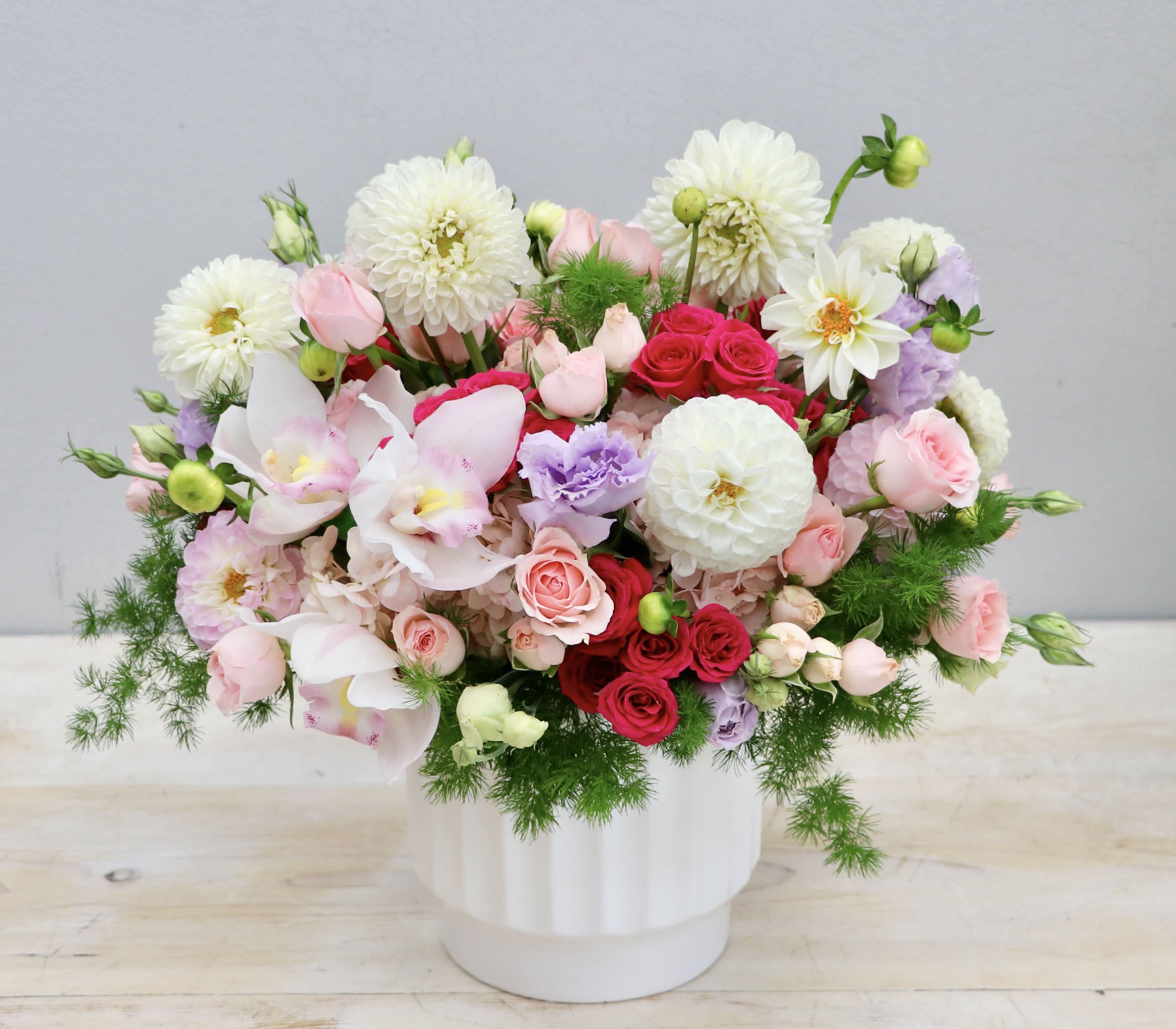 Mixed bouquet of pink, white, and red flowers in a white vase