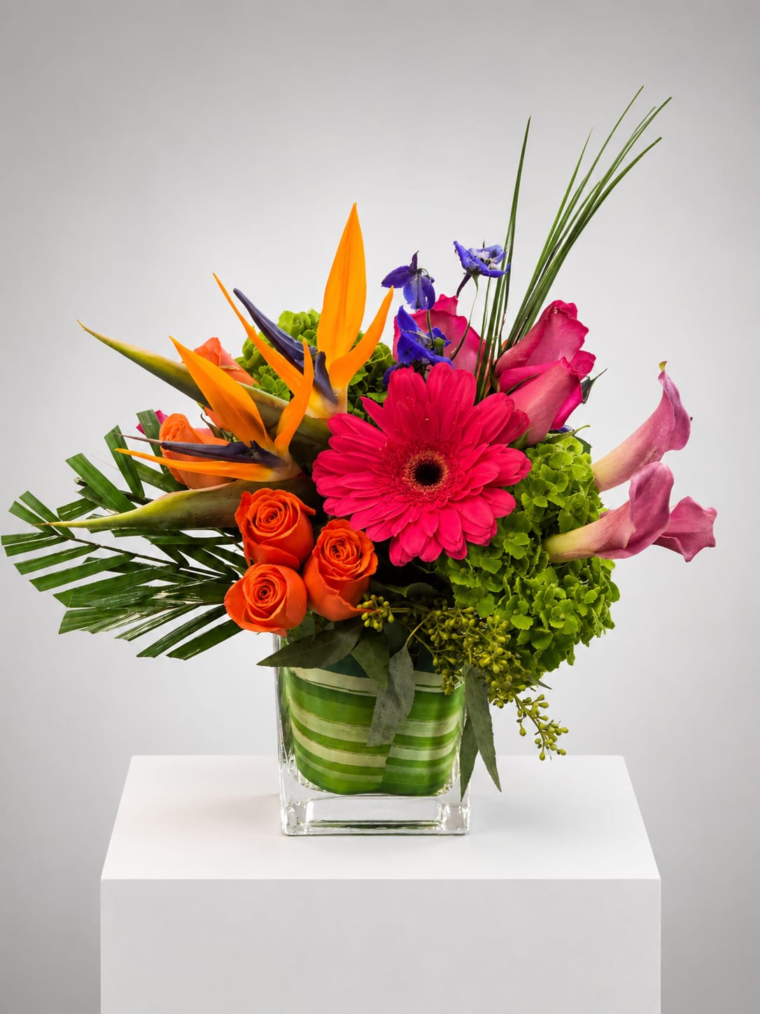 Bright mixed bouquet in a square glass vase with orange, pink, and purple blooms