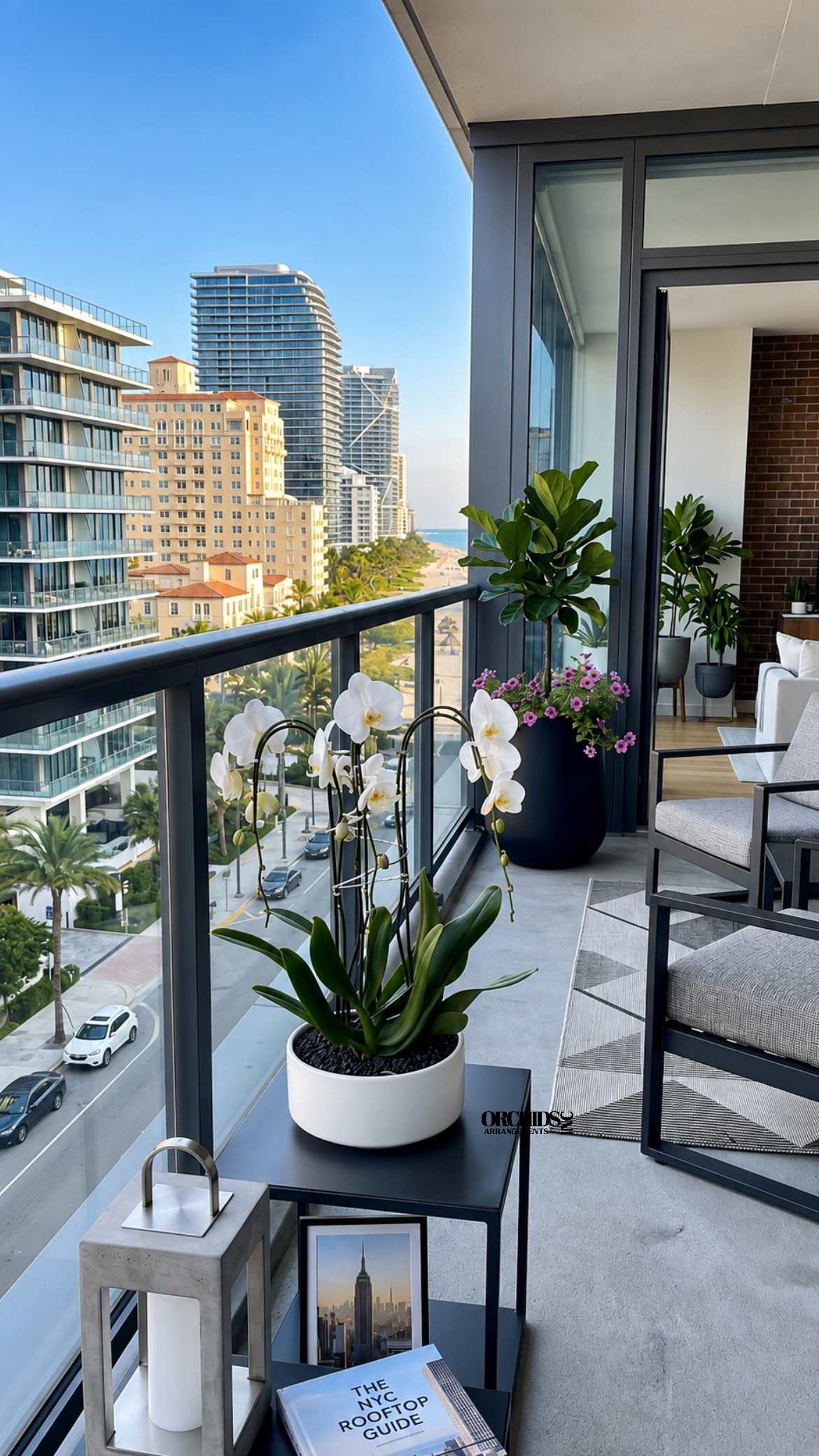 White orchids in a white pot on a balcony with city and ocean views.