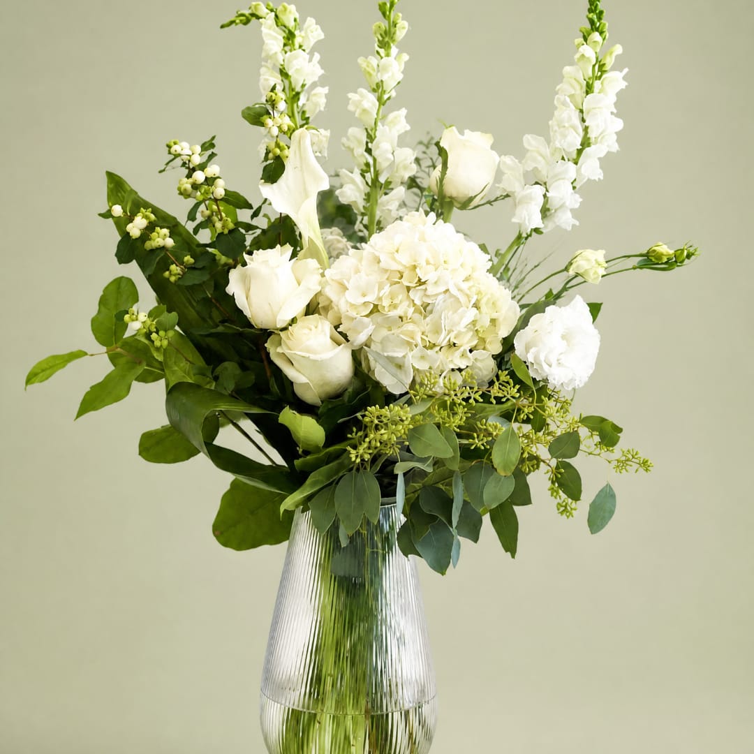 White flowers arranged in a clear ribbed glass vase