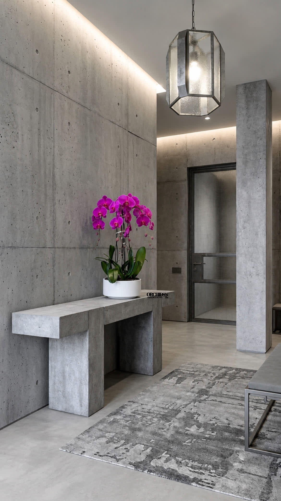 Potted pink orchid arrangement in a white planter on a concrete table