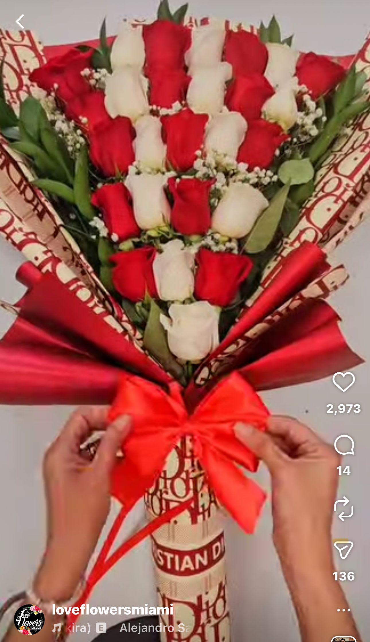 Bouquet of red and white roses wrapped in red paper with a bow.