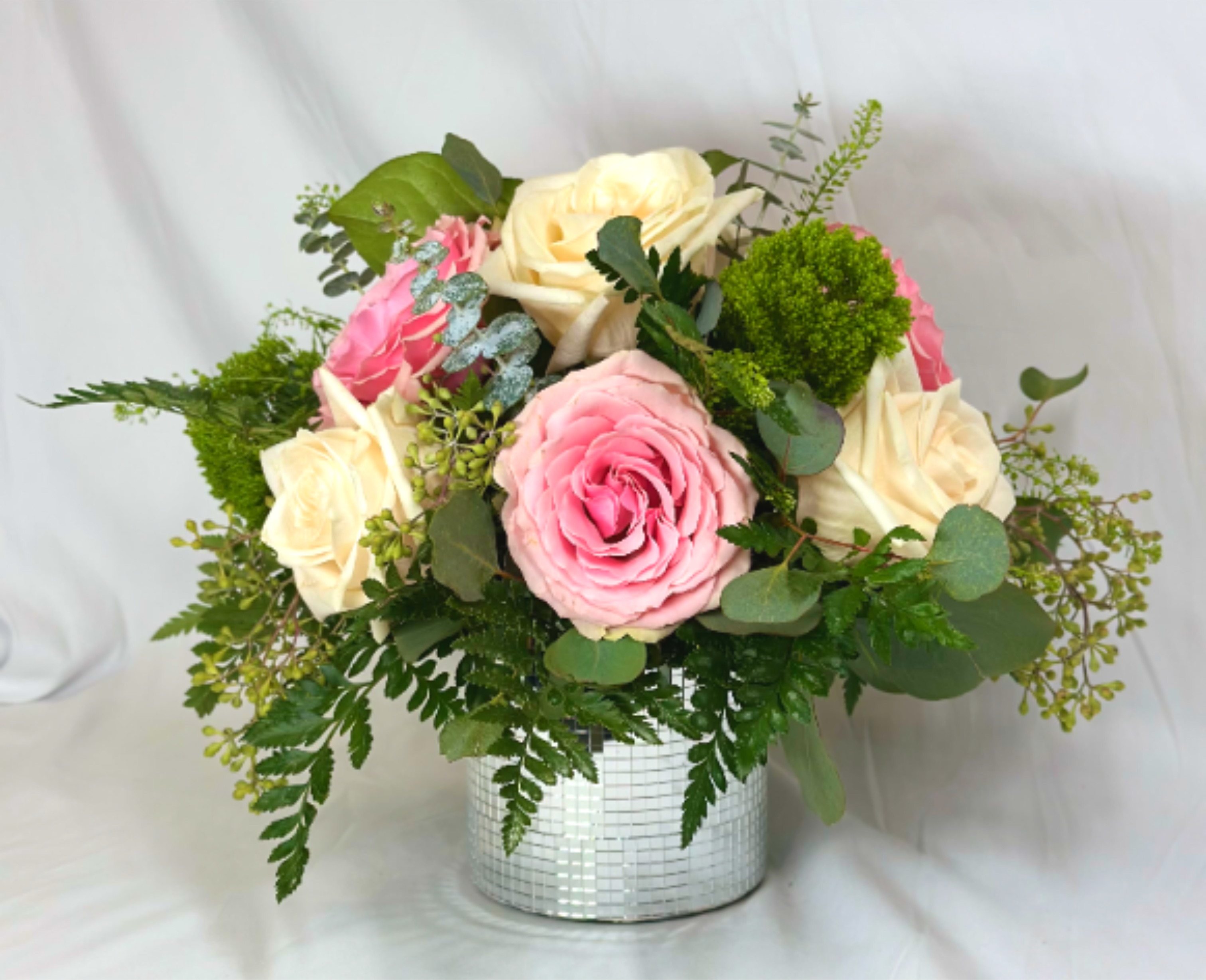 Pink and cream roses in a silver mosaic vase