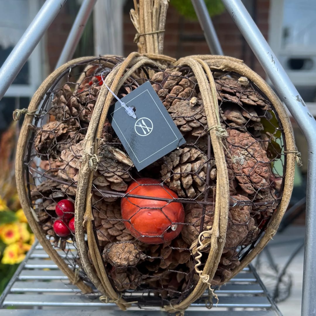 Wire pumpkin-shaped basket filled with pinecones and small decorative berries