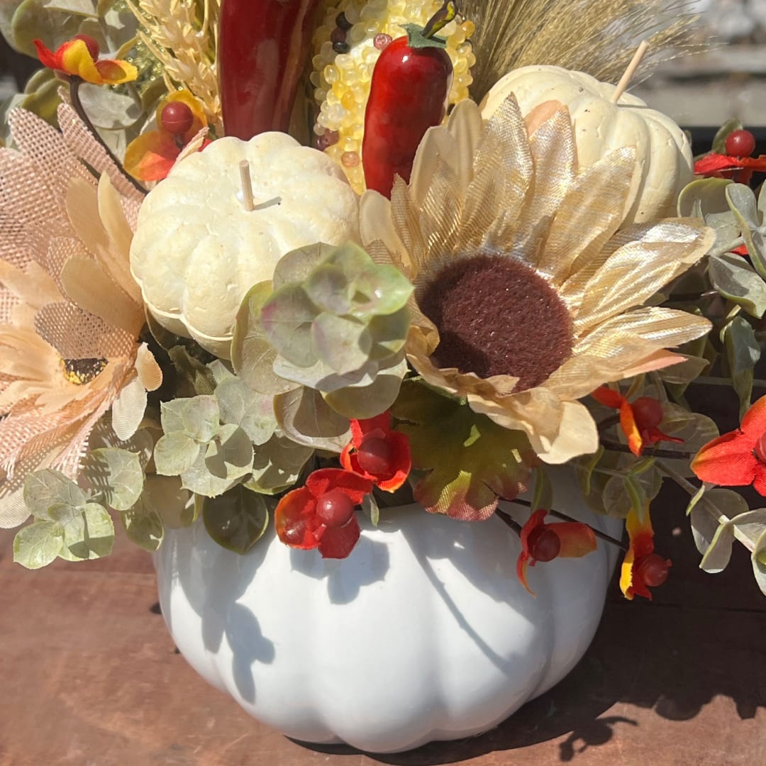 Fall floral arrangement in a white pumpkin container with sunflowers and pumpkins
