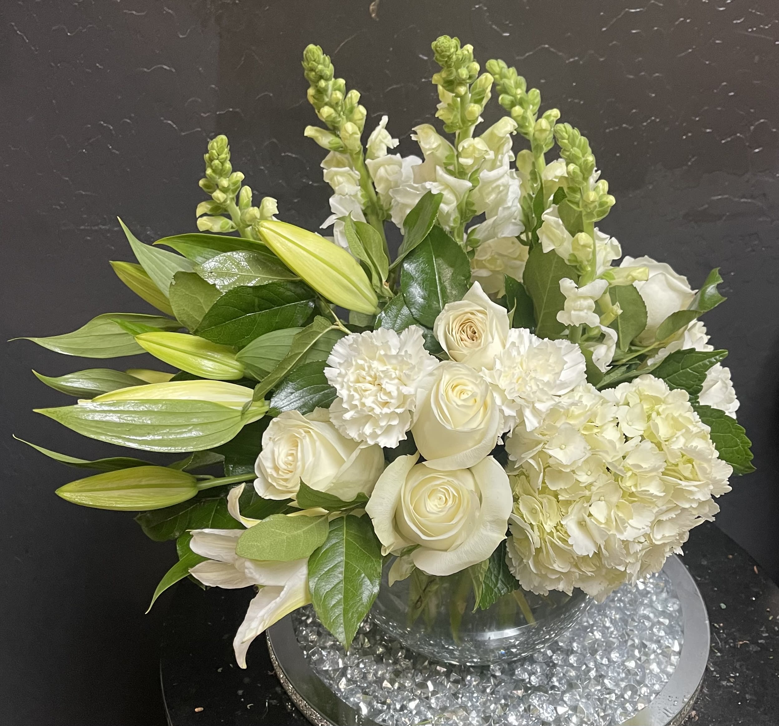 White roses and lilies arranged in a clear glass vase