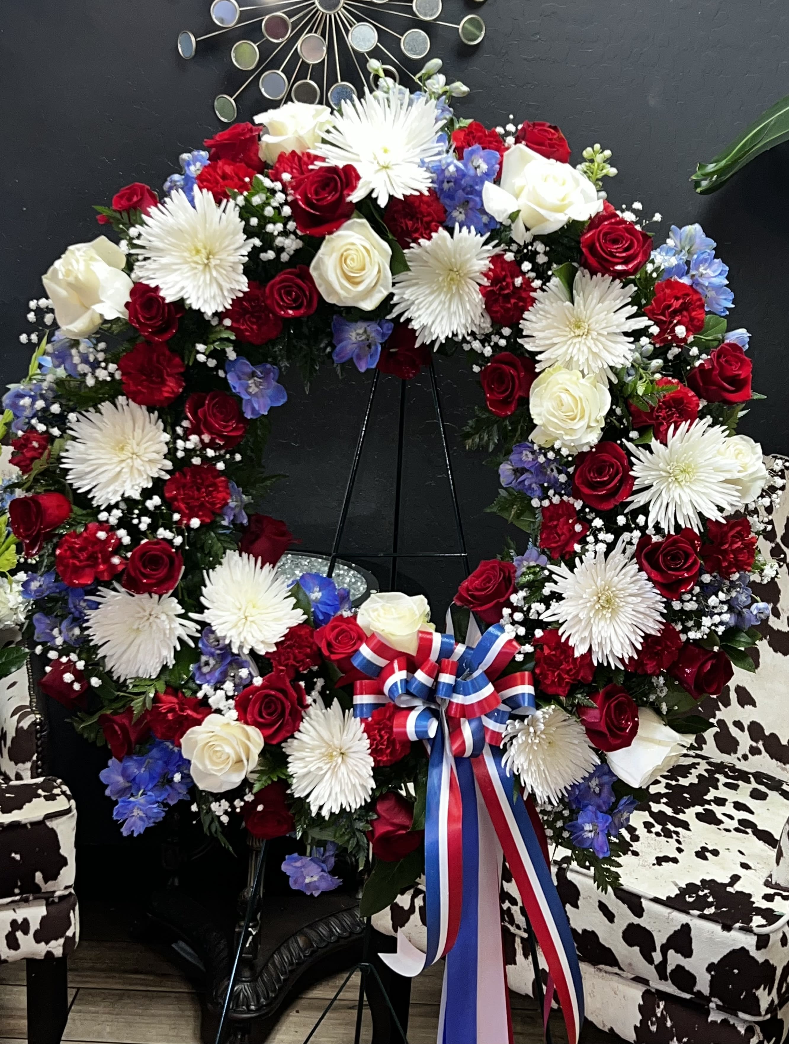 Circular wreath of red, white, and blue flowers on a stand