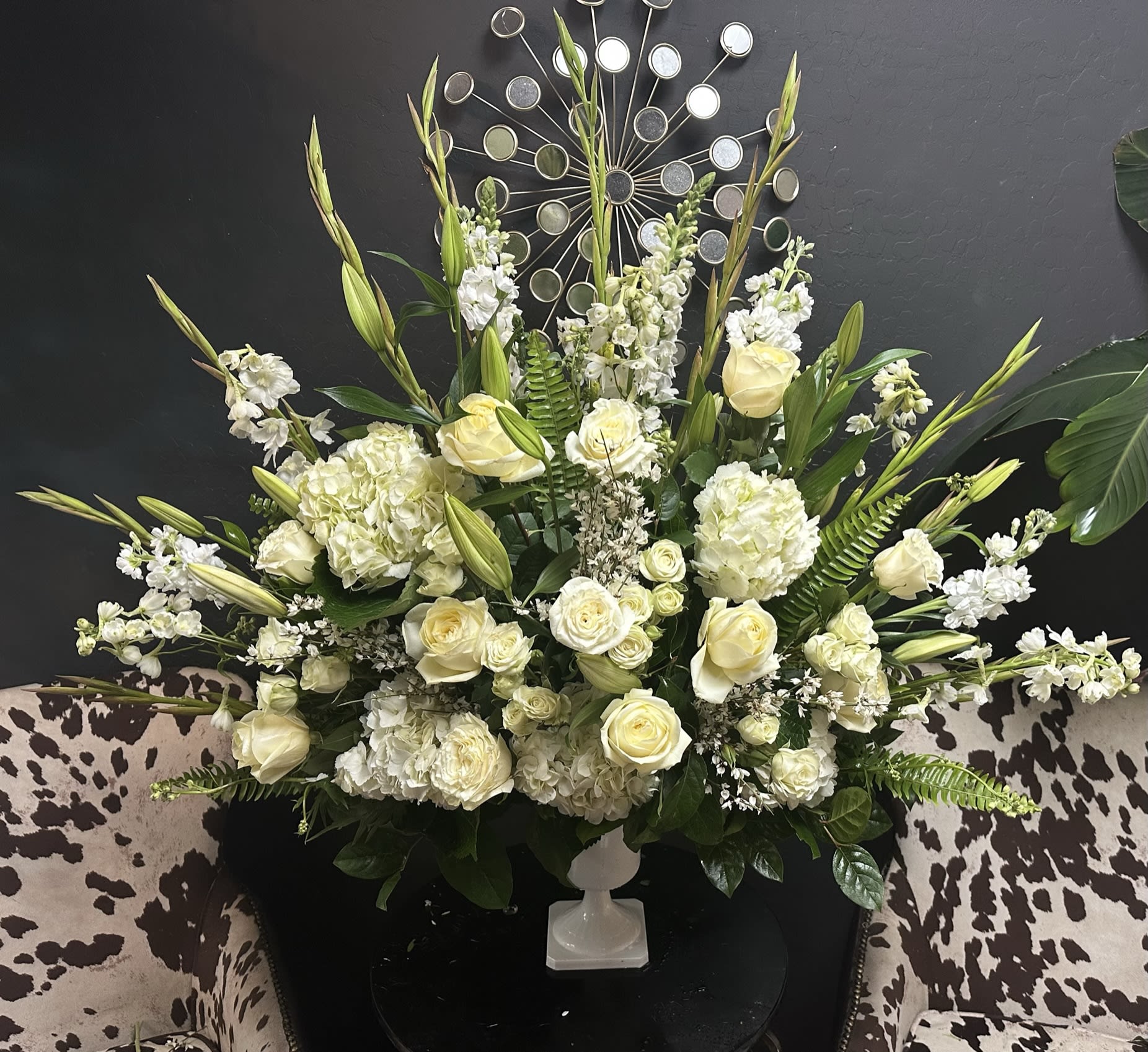 Large white floral arrangement in a white pedestal vase