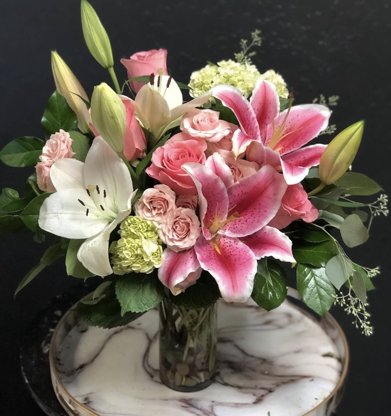 Pink lilies and roses arranged in a glass vase