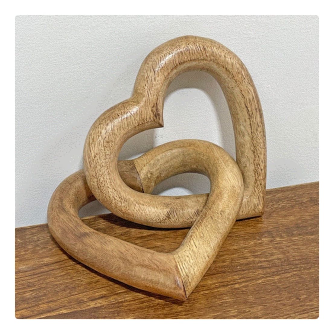 Two interlocking wooden heart sculptures on a tabletop