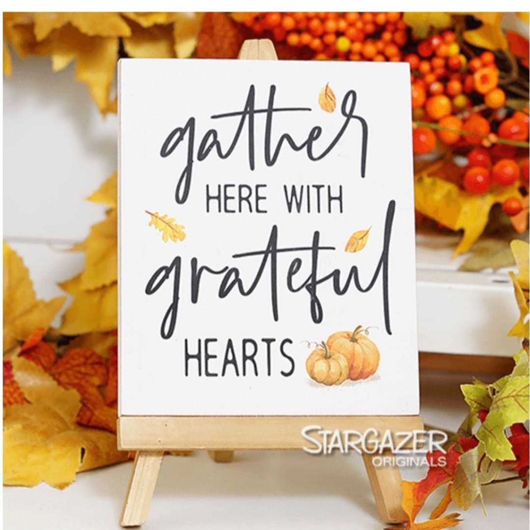 Fall sign on a small wooden easel reading "gather here with grateful hearts"