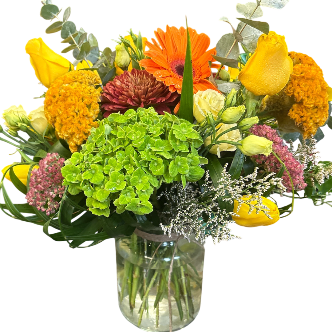 Mixed bouquet in a clear glass vase with yellow, orange, and pink flowers