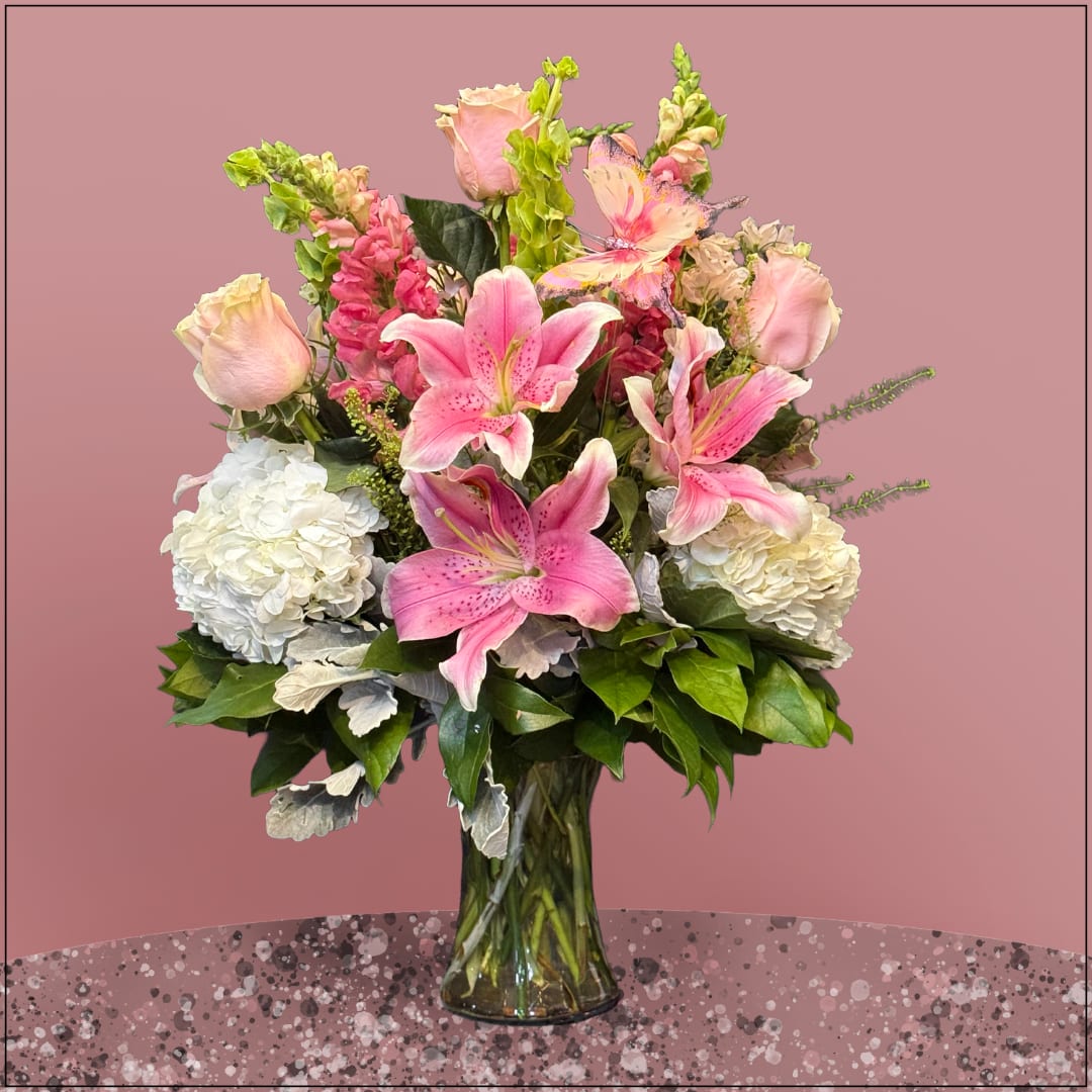 Pink lilies and white hydrangeas arranged in a clear glass vase