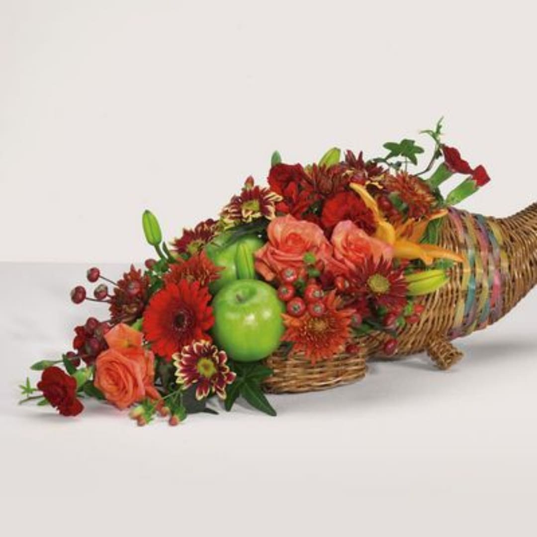 Basket arrangement of red and orange flowers with green apples