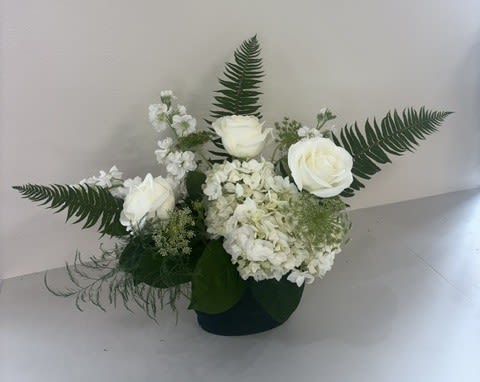 Botanical Whisper - A lush and elegant arrangement designed to evoke the beauty of a blooming garden. Presented in a rich green vase, this stunning design features crisp white roses, cloud-like hydrangeas, and fragrant stock, artfully arranged to create texture, movement, and natural charm. The fresh white blooms contrast beautifully with the verdant vessel, creating a timeless look that is both sophisticated and serene. Perfect for celebrations, sympathy expressions, or adding a touch of garden-inspired elegance to any space.