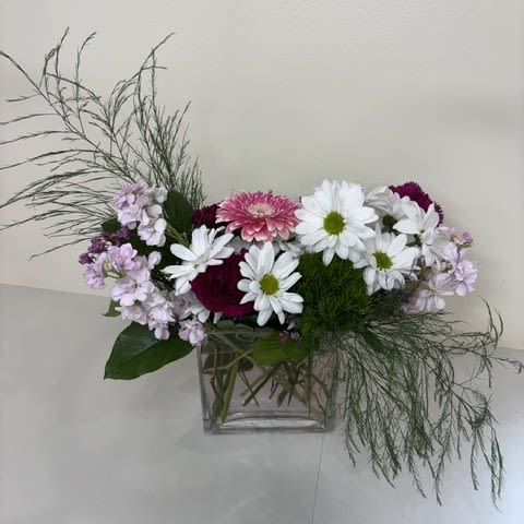 Daisy Daydream - Soft, cheerful, and full of charm, Daisy Daydream is a delightful arrangement featuring crisp white daisies, fragrant pink stock, vibrant green trick dianthus, rich purple carnations, and a stunning pink gerbera daisy. Thoughtfully designed to capture the beauty of a blooming garden, this arrangement brings together fresh colors and textures for a look that is both whimsical and elegant. Perfect for birthdays, celebrations, thank-you gifts, or simply brightening someone's day, Daisy Daydream is a sweet reminder that life's most beautiful moments are often the simplest.