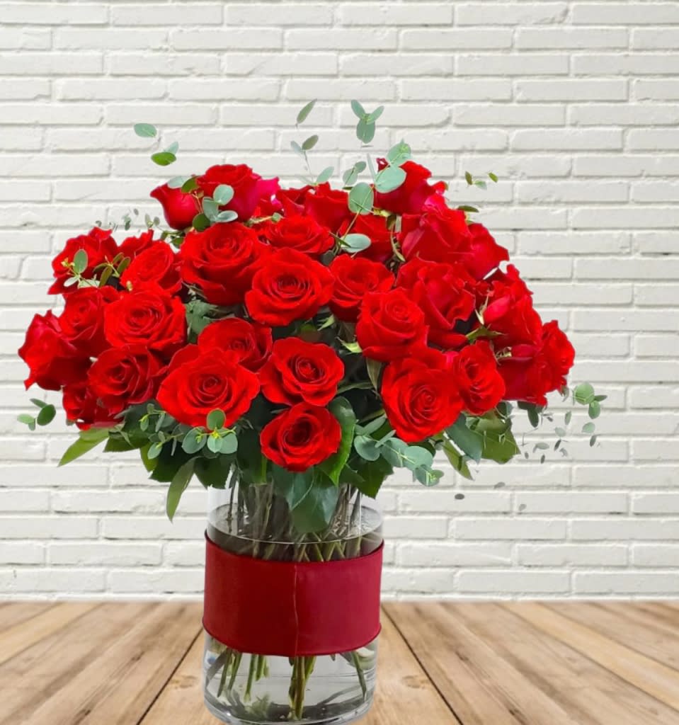 Bouquet of red roses in a clear glass vase with a red wrap
