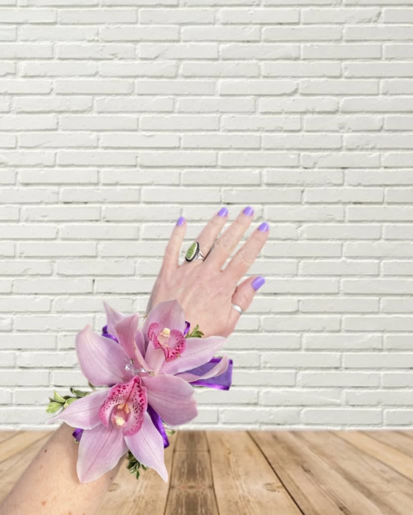 Pink orchid corsage on a wrist with purple ribbon