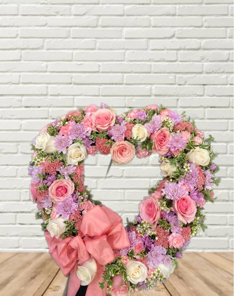 Heart-shaped floral wreath with pink and lavender roses and a large pink bow