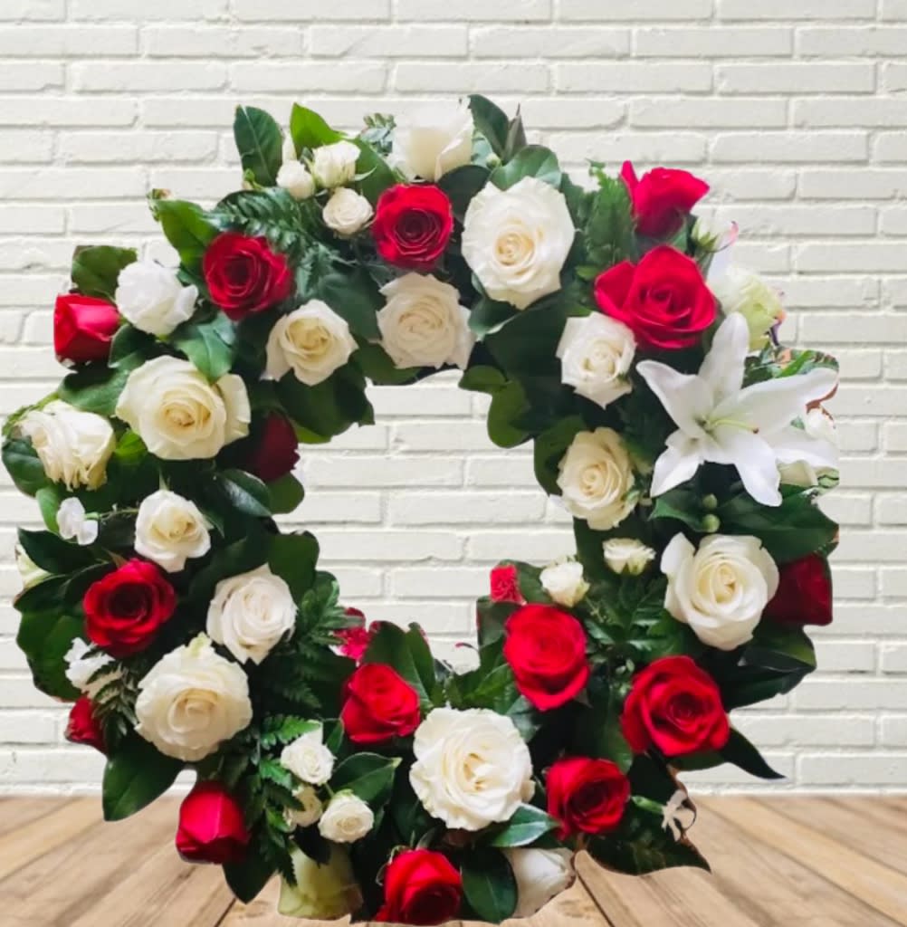 Circular wreath of red and white roses with a white lily