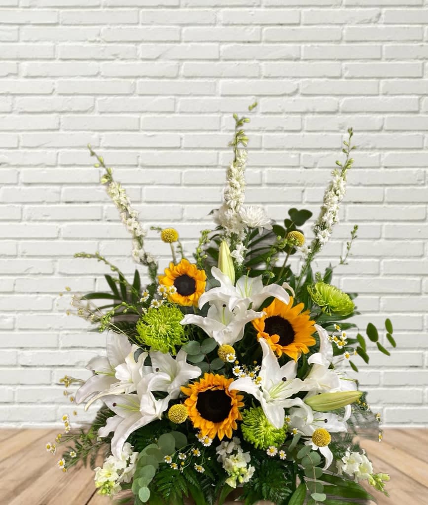 Arrangement of white lilies and sunflowers with green accents