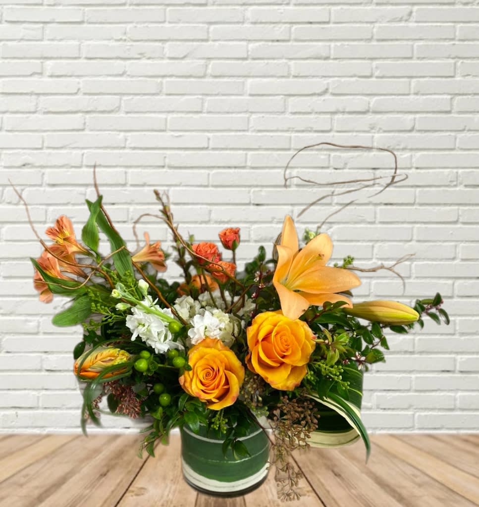 Orange roses and lilies arranged in a green vase