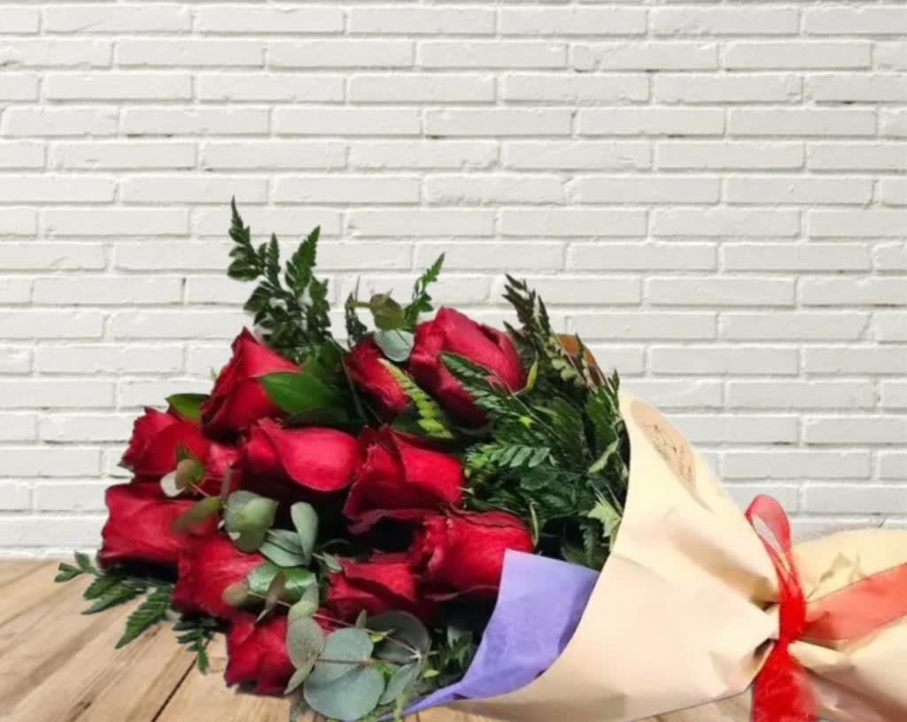 Bouquet of red roses wrapped in cream paper with a red ribbon