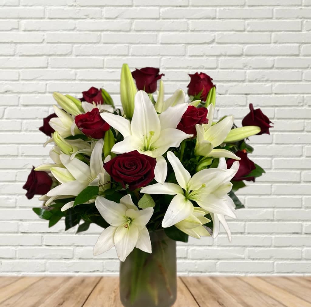 Bouquet of white lilies and deep red roses in a glass vase