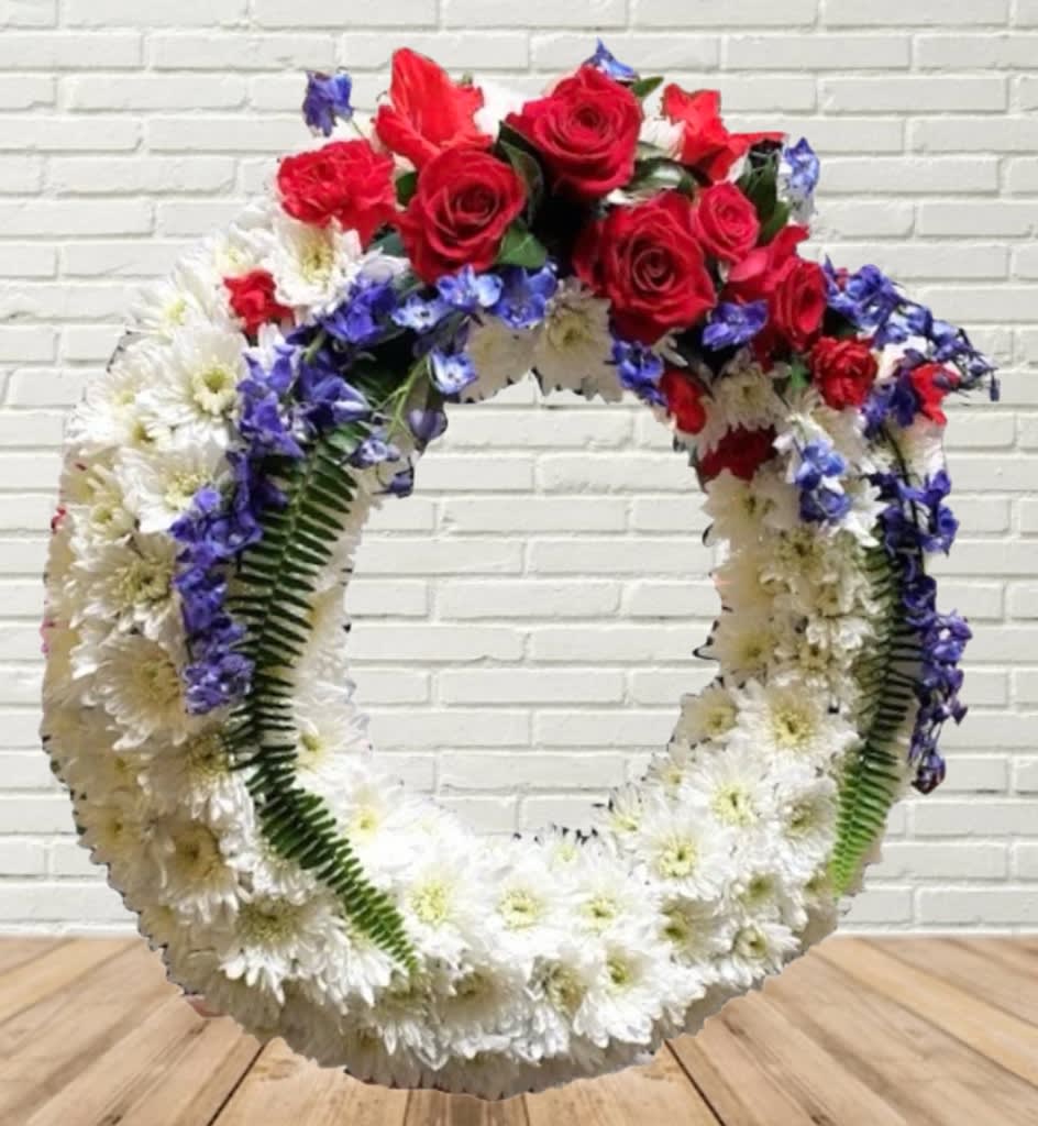 Large floral wreath with red roses, white daisies, and blue flowers