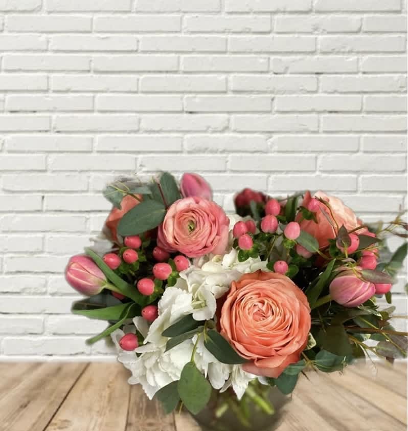 Bouquet of coral roses, pink tulips, and white hydrangeas in a vase