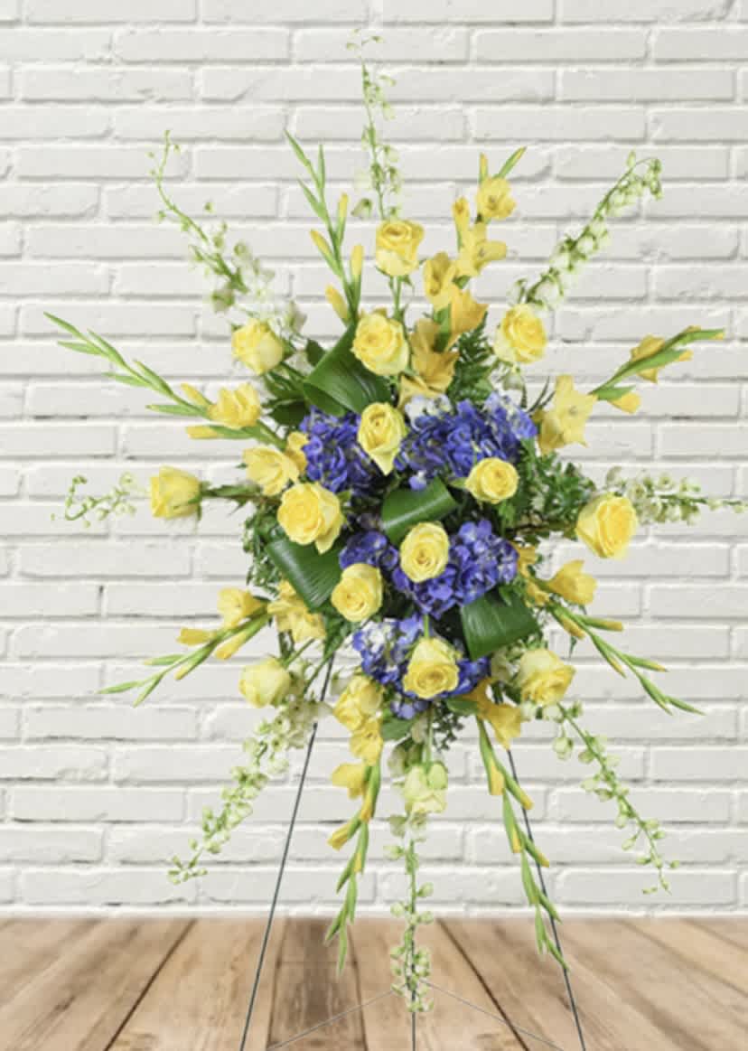 Yellow roses and purple flowers in a standing spray on an easel