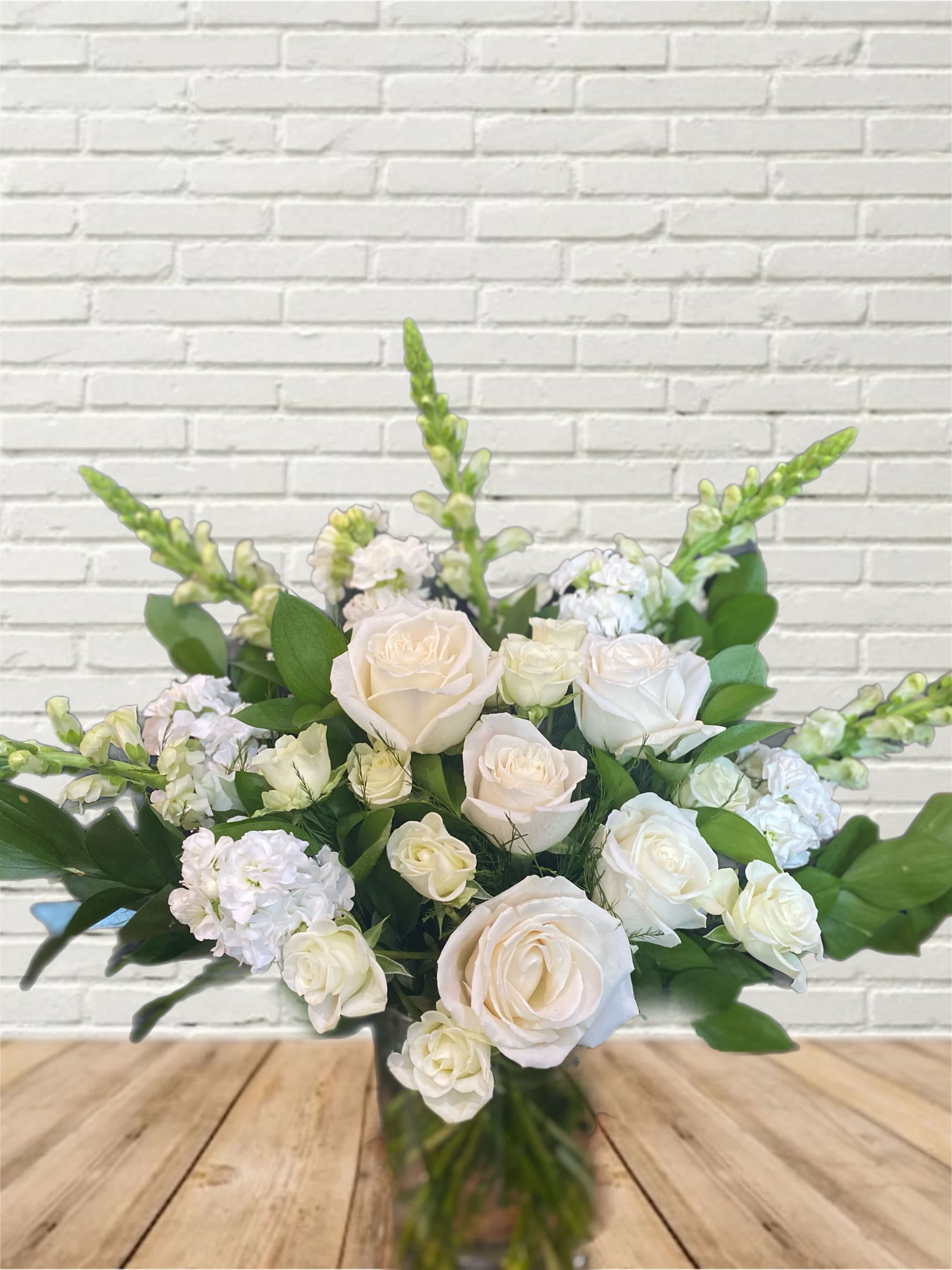White roses and pale blooms arranged in a glass vase
