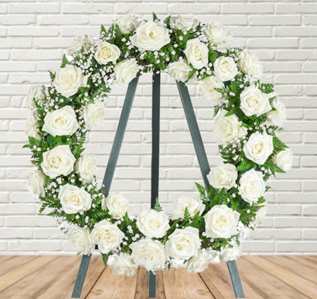 White rose wreath on a standing easel with dark ribbon