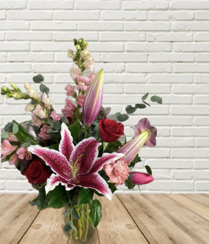 Bouquet of pink lilies and red roses in a glass vase