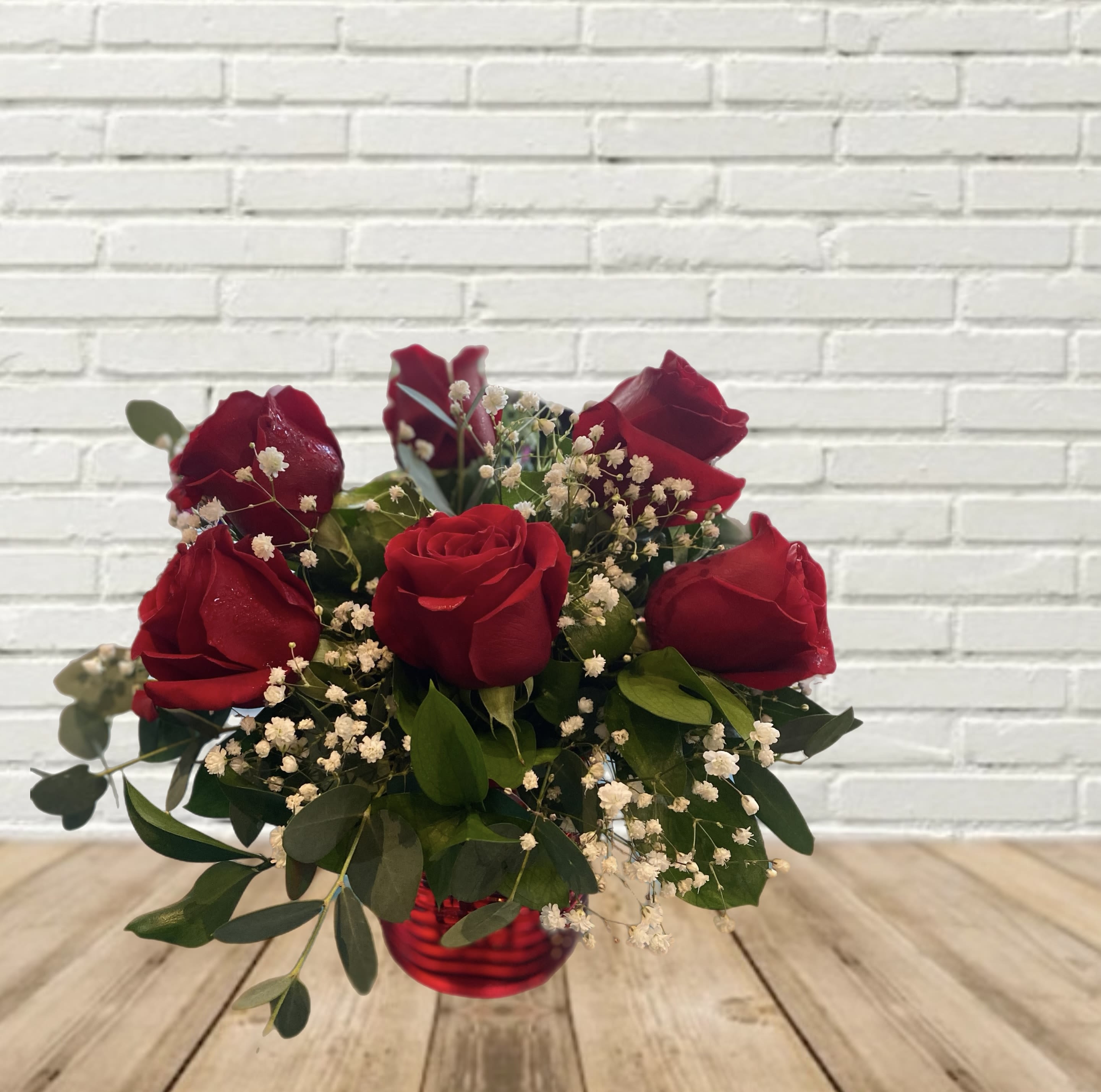 Red roses in a red glass vase with baby's breath