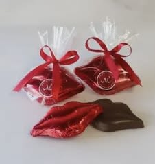 Two red ribbon-tied gift bags with chocolates and a red foil lips-shaped candy