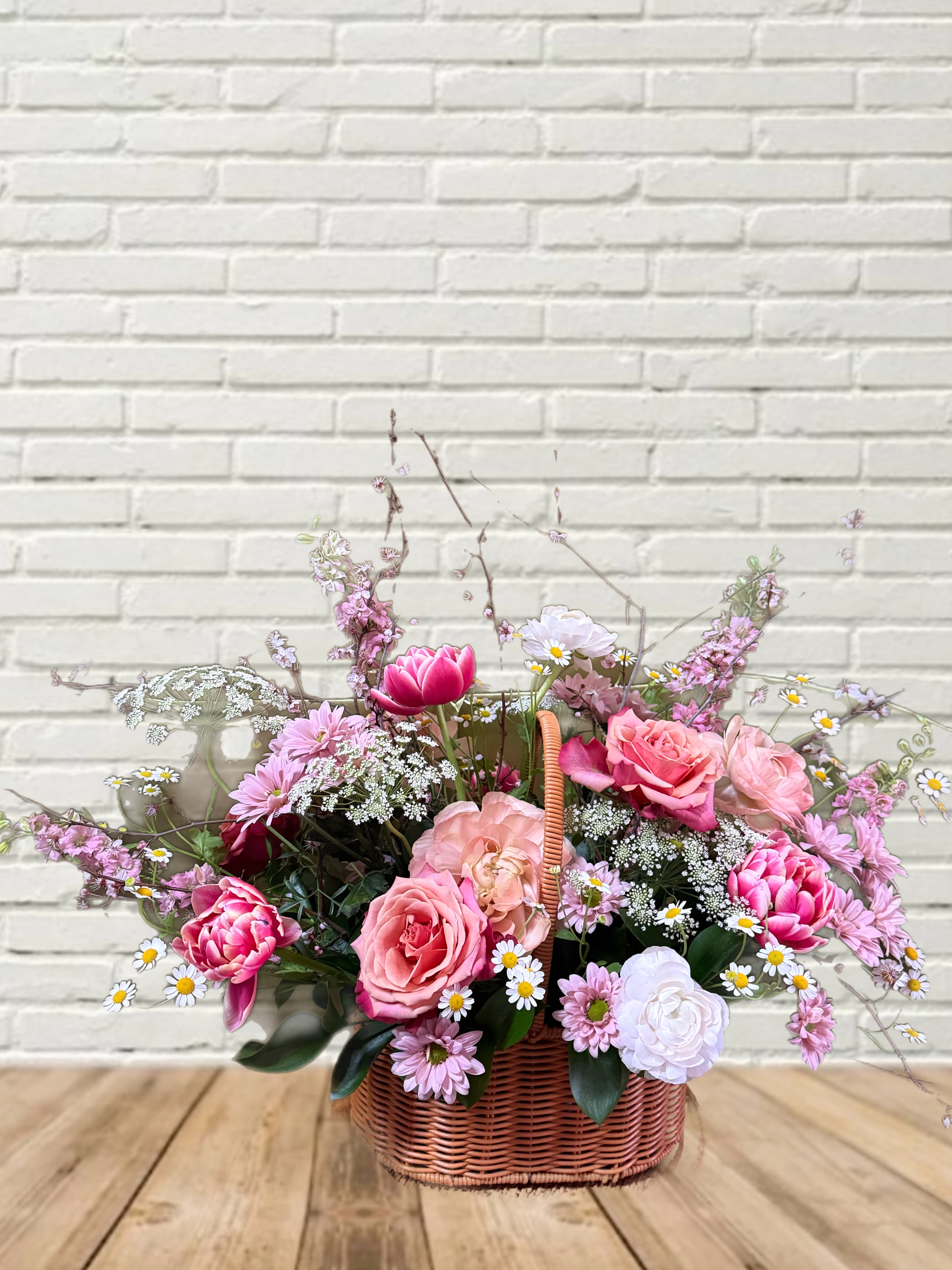 Pink and white mixed flower arrangement in a wicker basket