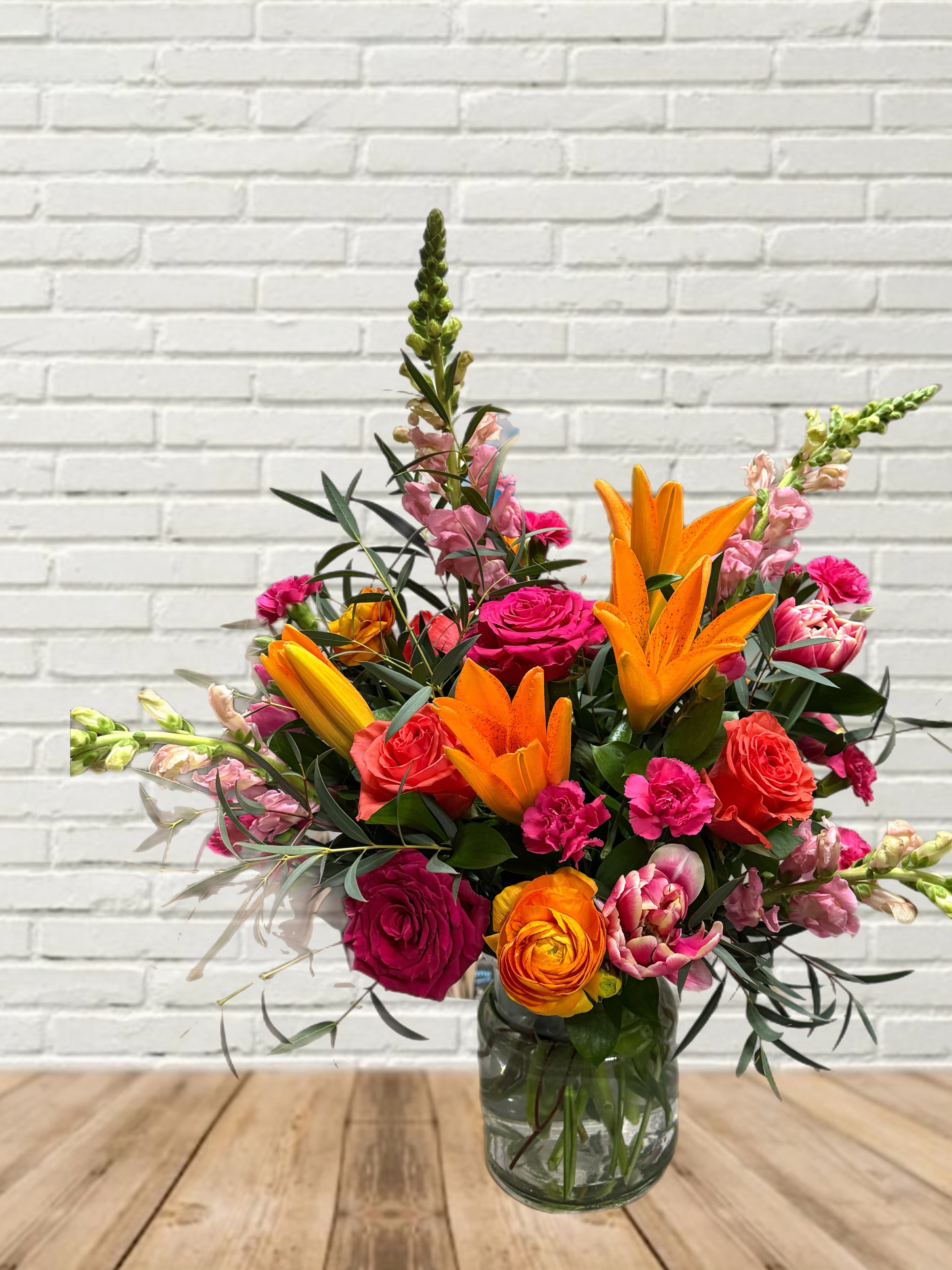 Bright mixed bouquet with orange lilies and pink roses in a glass vase