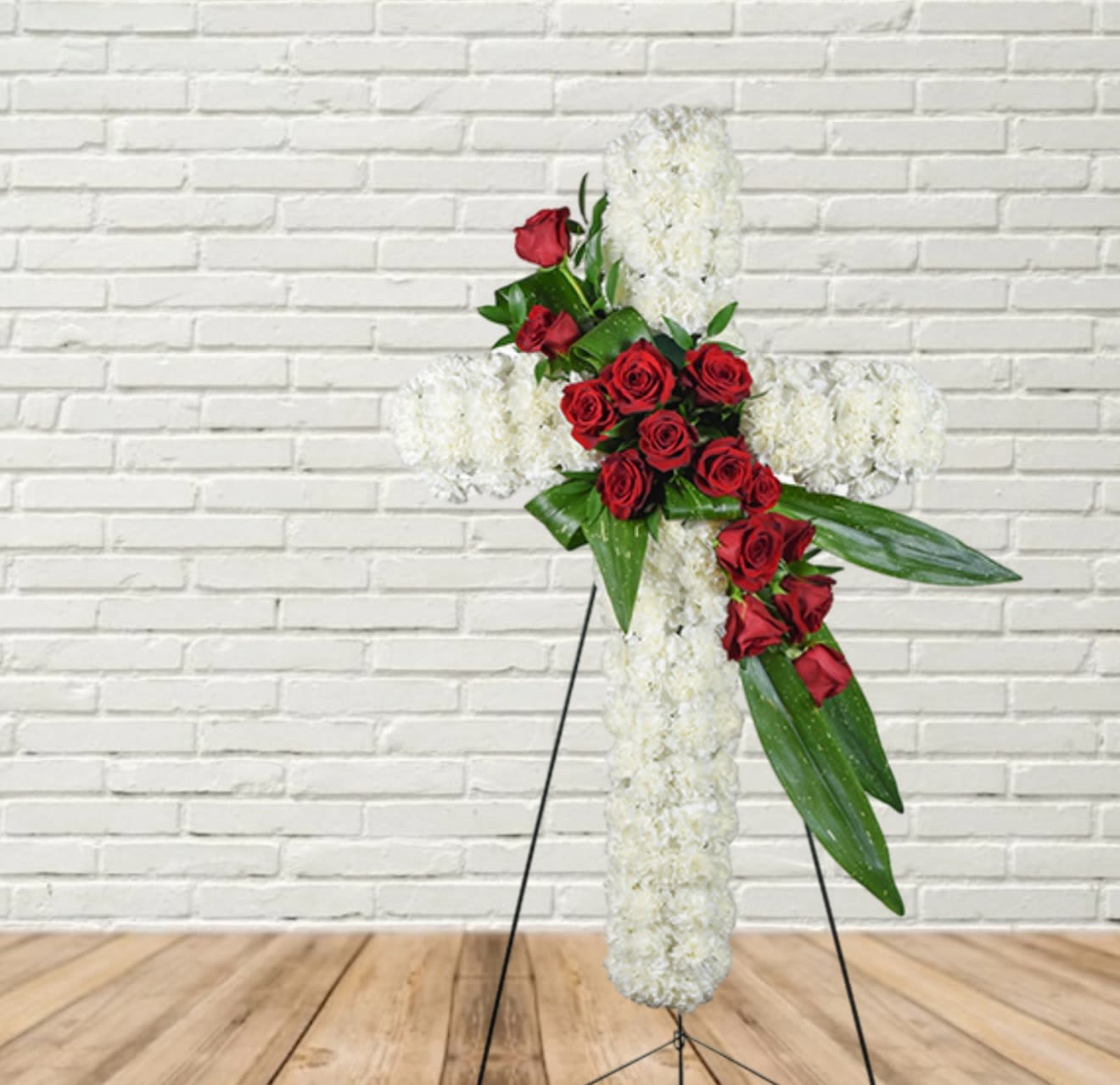 White floral cross with red roses on a stand