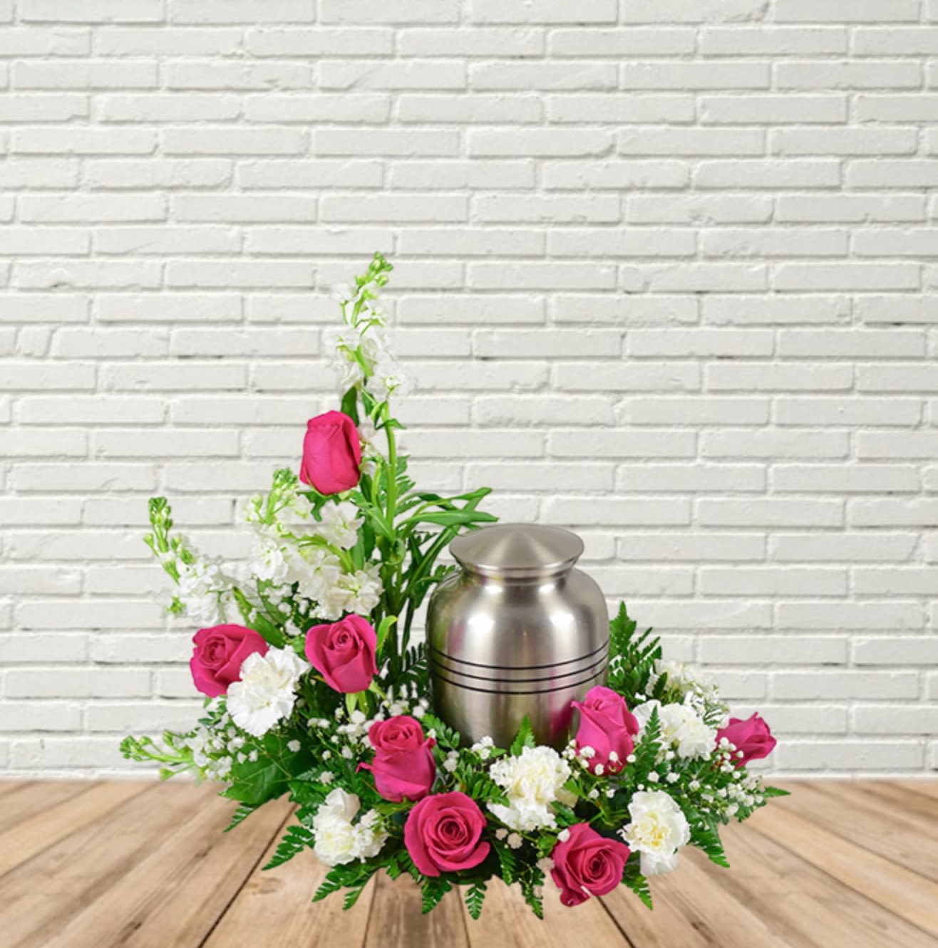 Pink roses and white flowers arranged around a silver urn