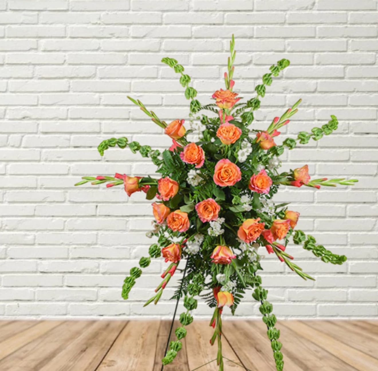 Orange roses in a tall standing floral spray with green accents