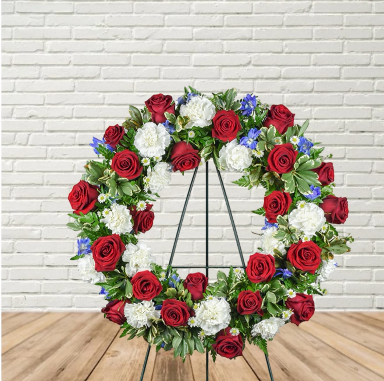 Circular wreath of red and white flowers on a black stand