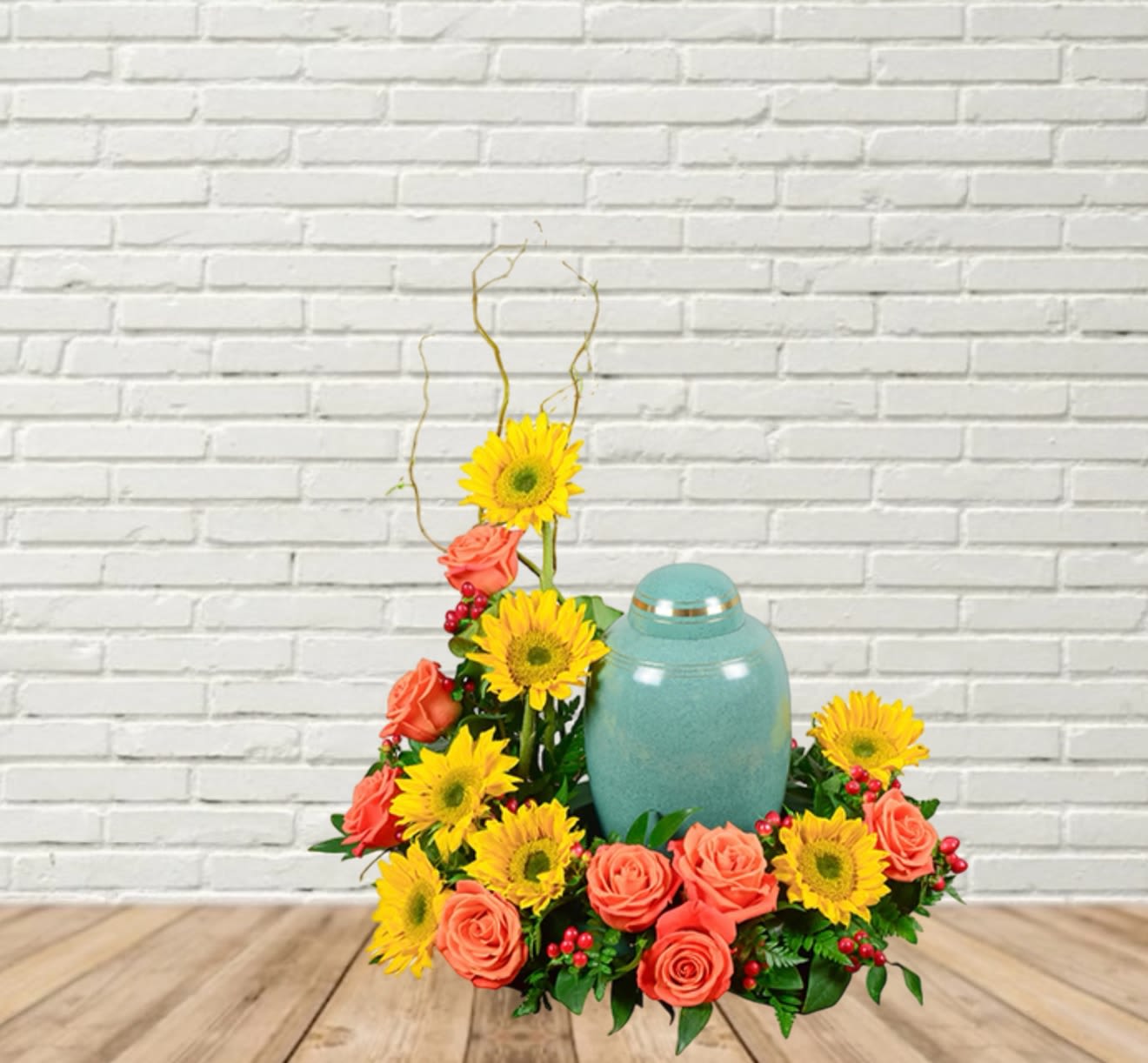 Coral roses and yellow sunflowers arranged around a teal urn.