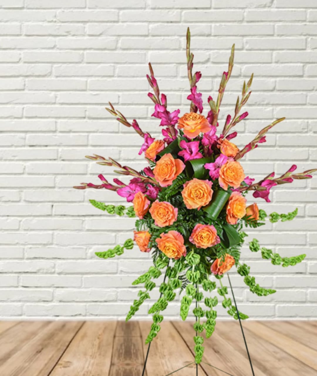 Orange roses and magenta flowers in a tall standing arrangement