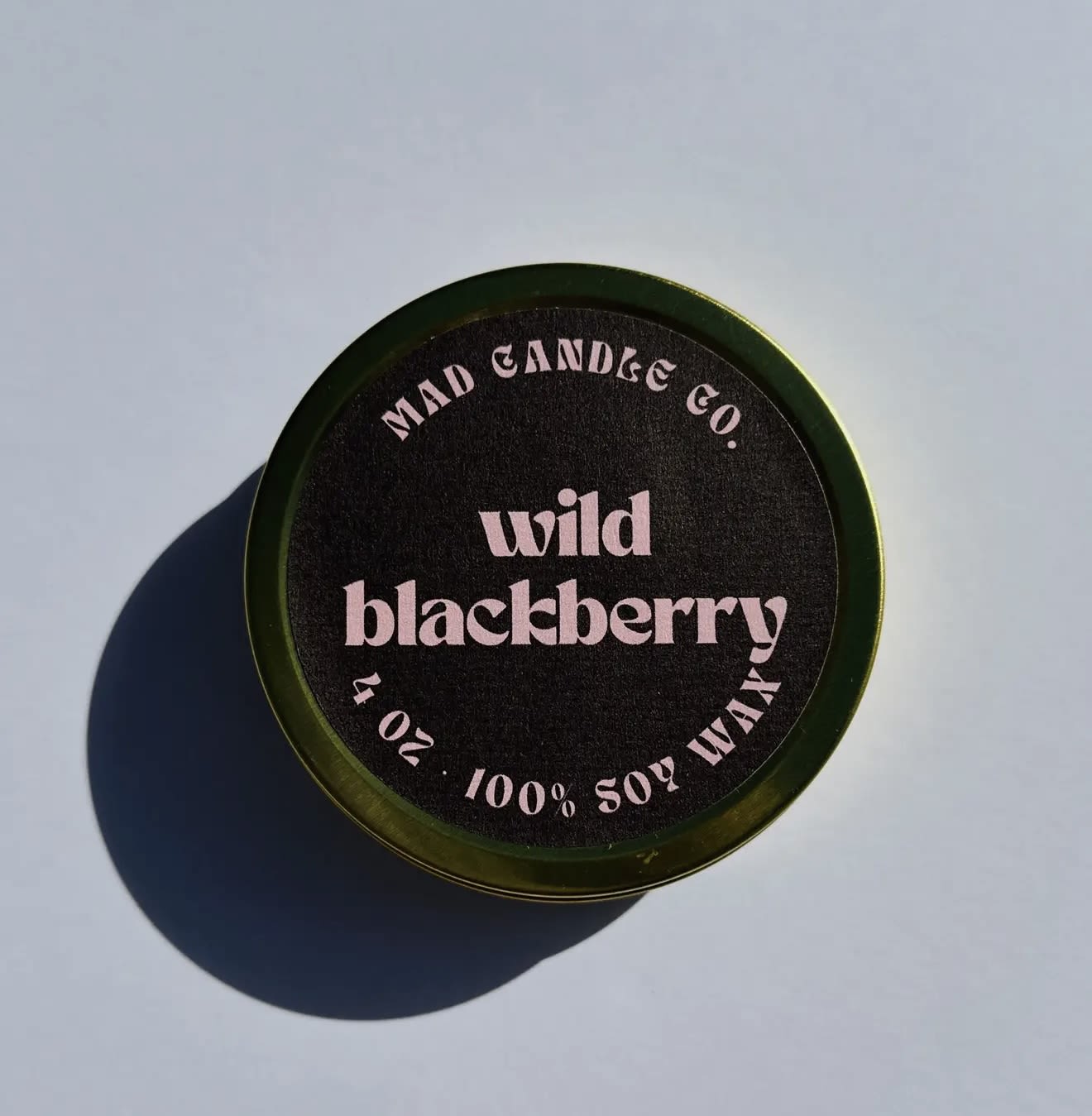 Round candle tin labeled wild blackberry on a light surface