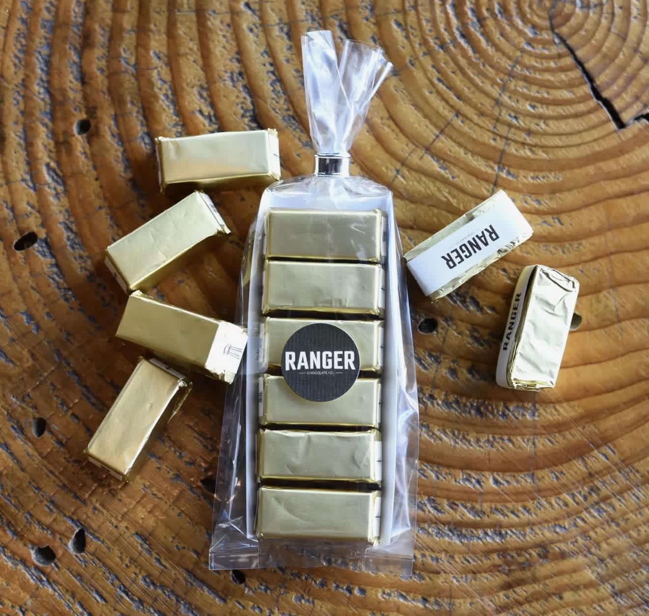 Wrapped candy bars and gold foil chocolates arranged around a clear gift bag