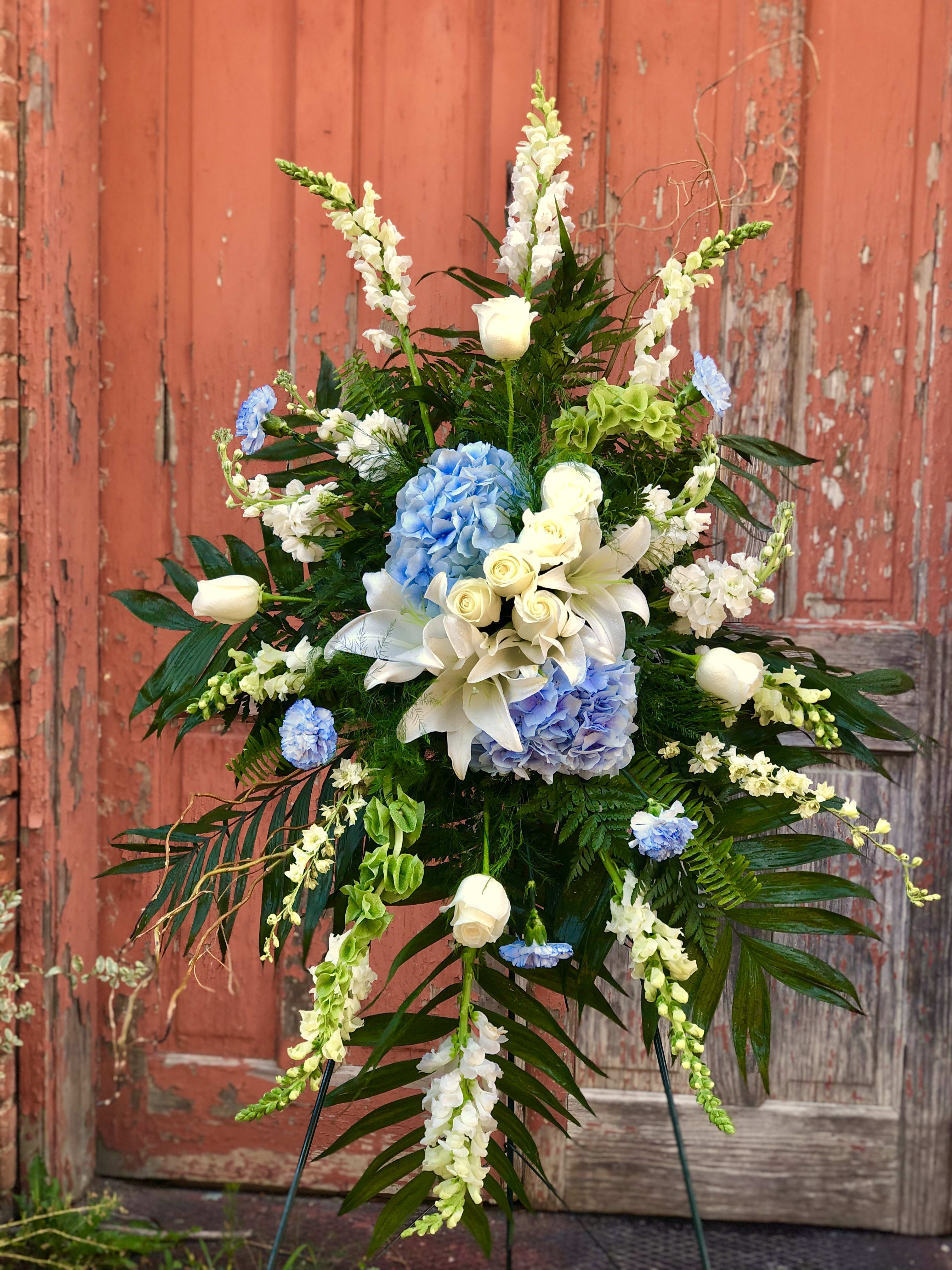 Tall floral spray with white lilies, blue hydrangeas, and white roses