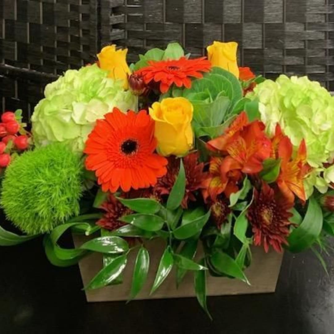 Bright mixed flower arrangement in a rectangular box with orange and yellow blooms
