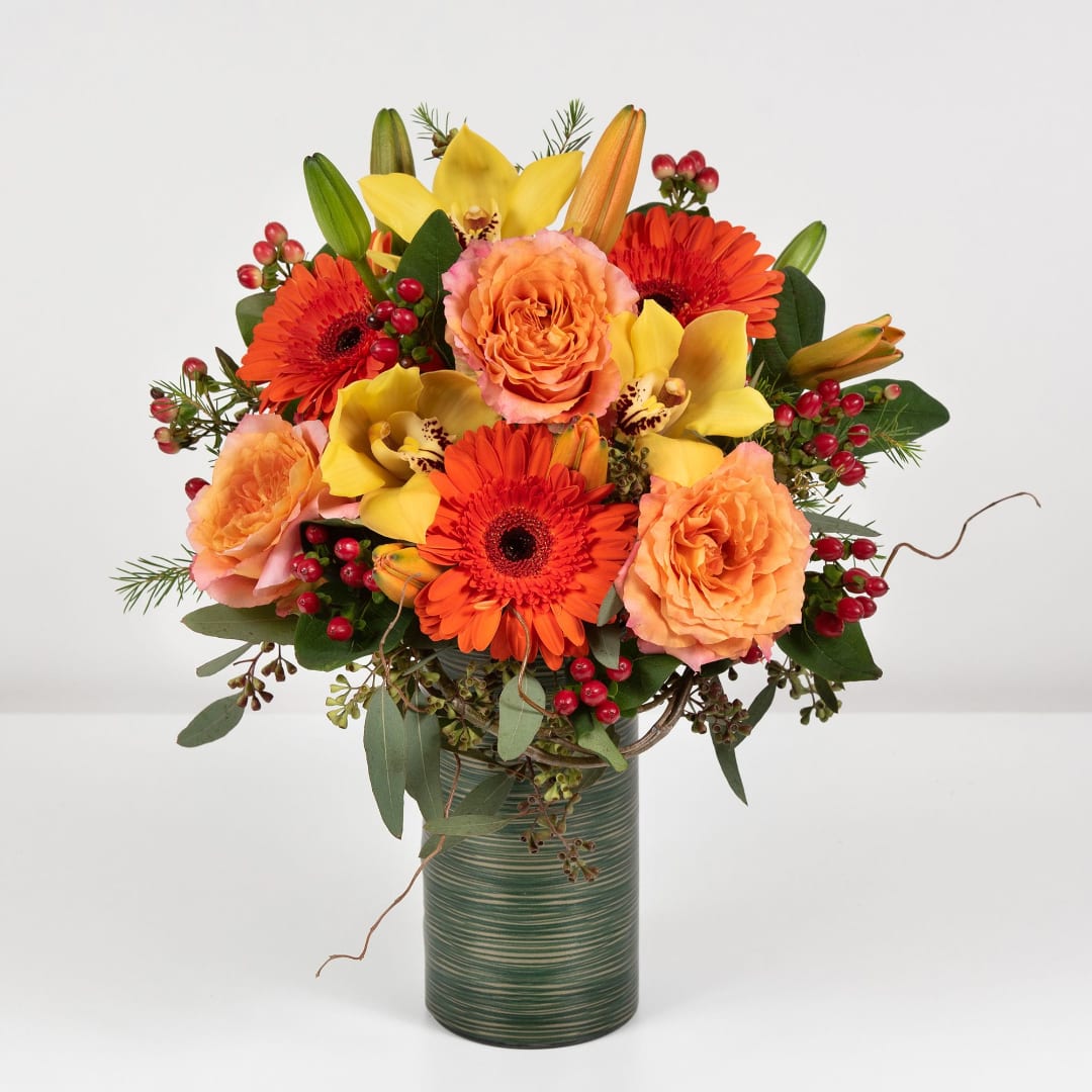 Orange and yellow mixed flower arrangement in a green vase